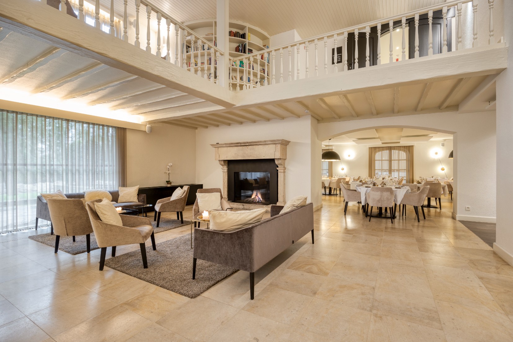Atmospheric lounge with fireplace and mezzanine library at Corsendonk Hooge Heyde